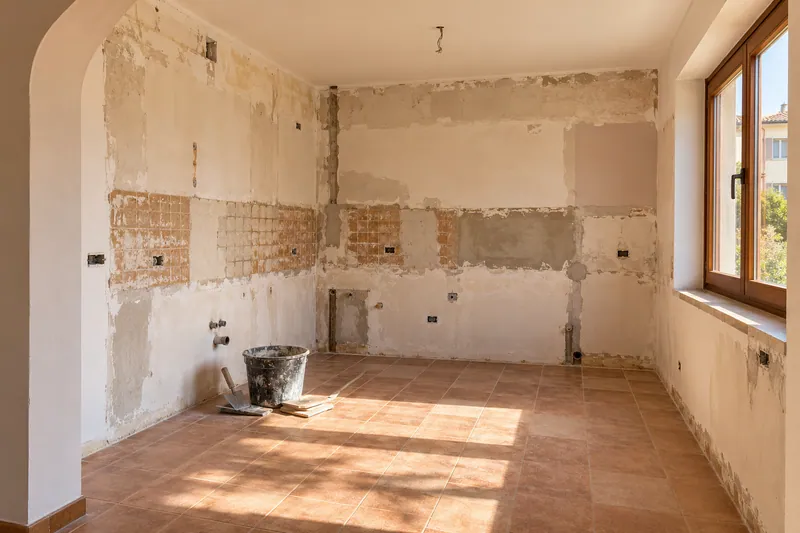 Visualización conceptual IA: Cocina sin muebles con paredes en preparación y zonas de enlucido.